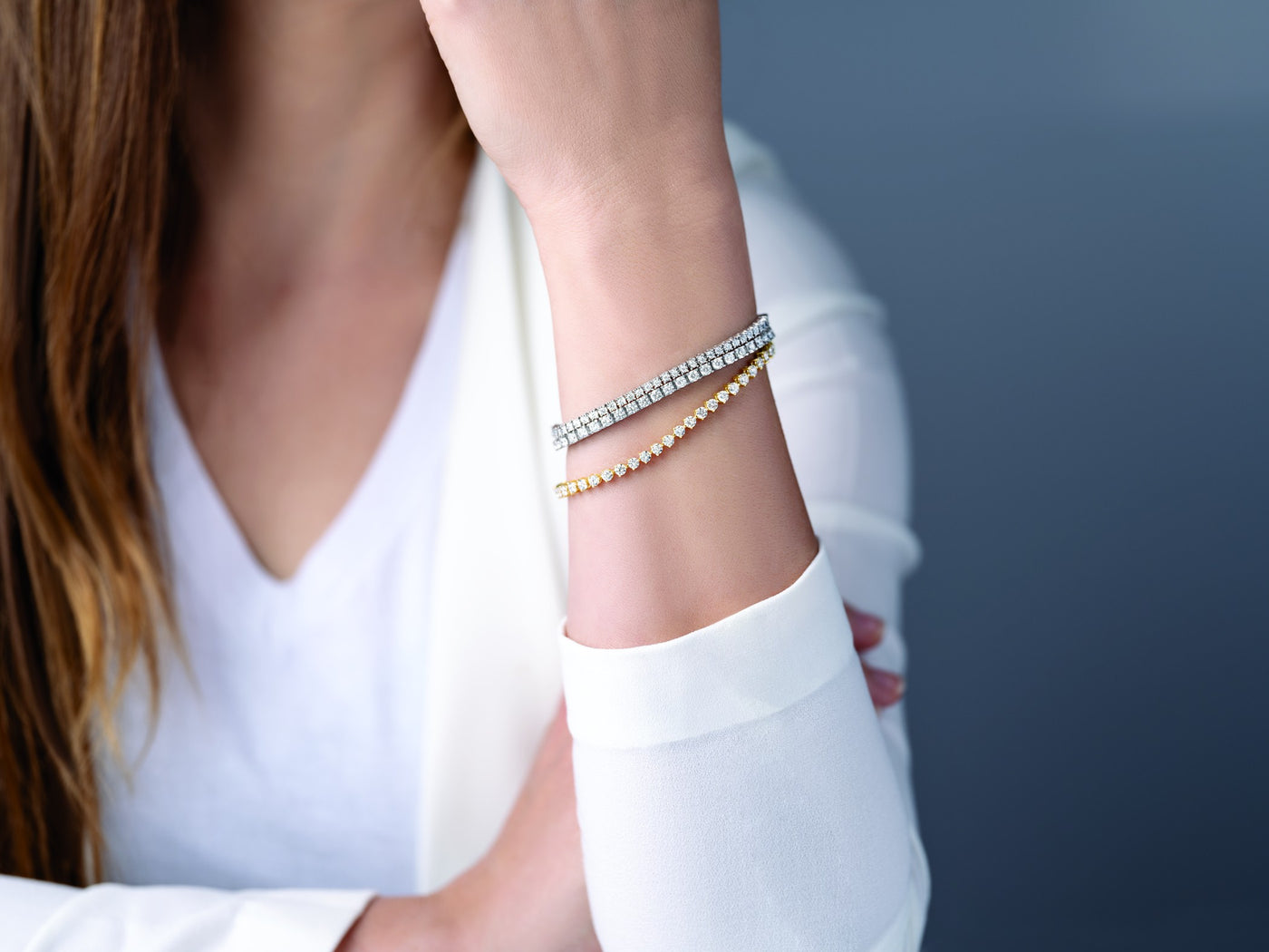 Woman wearing two stacked lab-grown diamond tennis bracelets in white and yellow gold at Farsi Jewelers