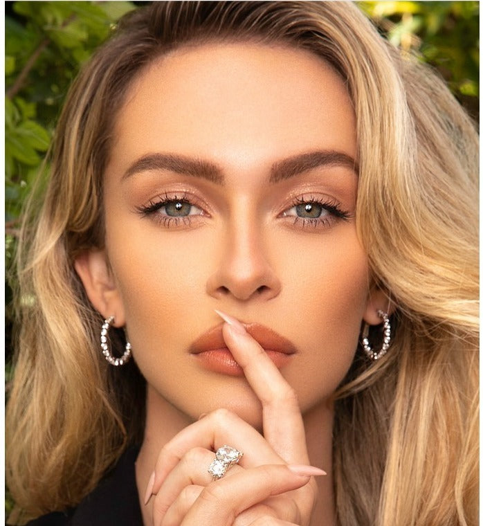 Close-up of a model wearing sterling silver hoop earrings and a diamond ring at Farsi Jewelers