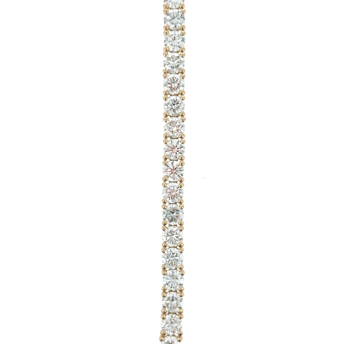 Close-up of the straight line of round lab-grown diamonds in yellow gold four-prong settings