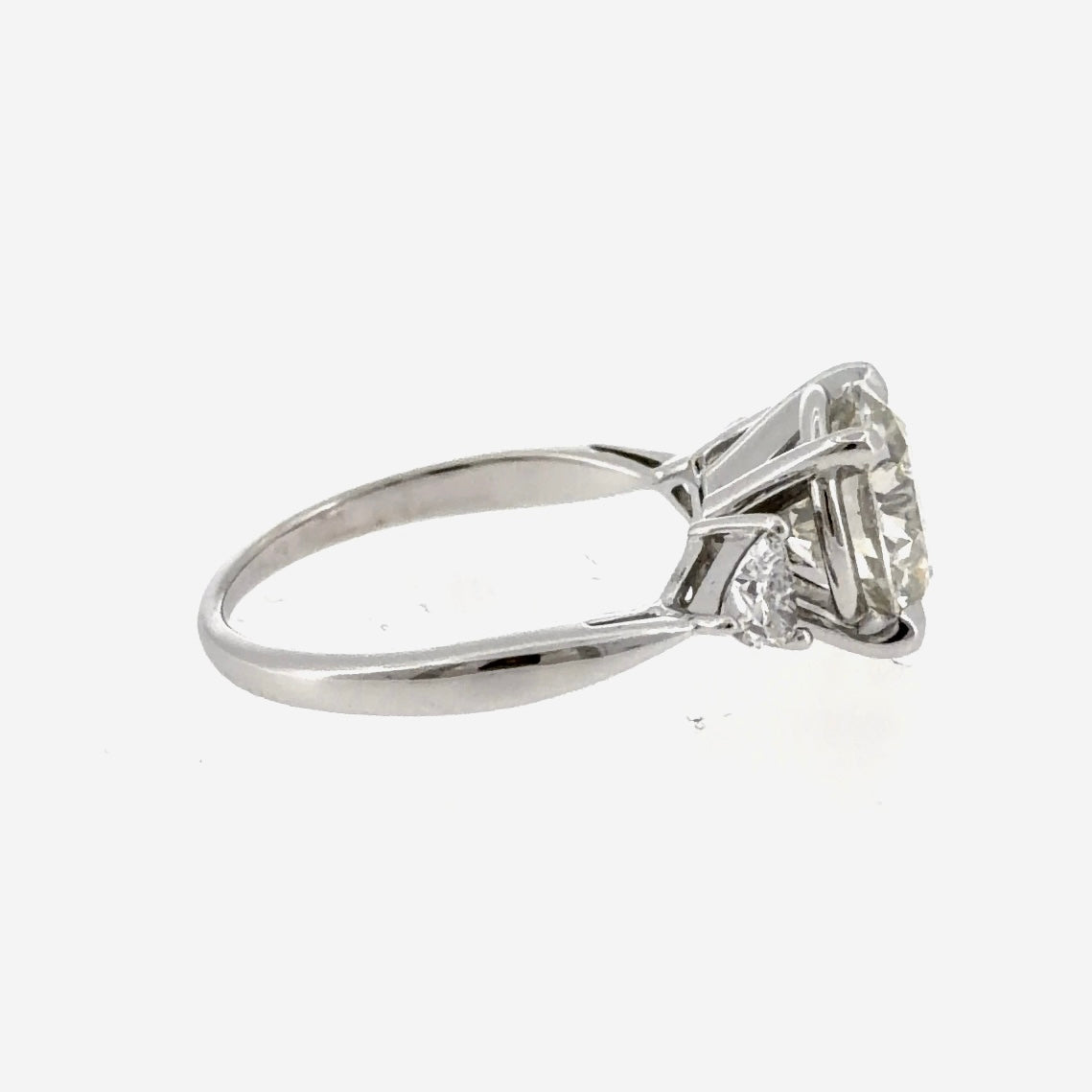 Side view of the 14K white gold trillion three-stone engagement ring and its four-prong head, shown with a center stone that is not included