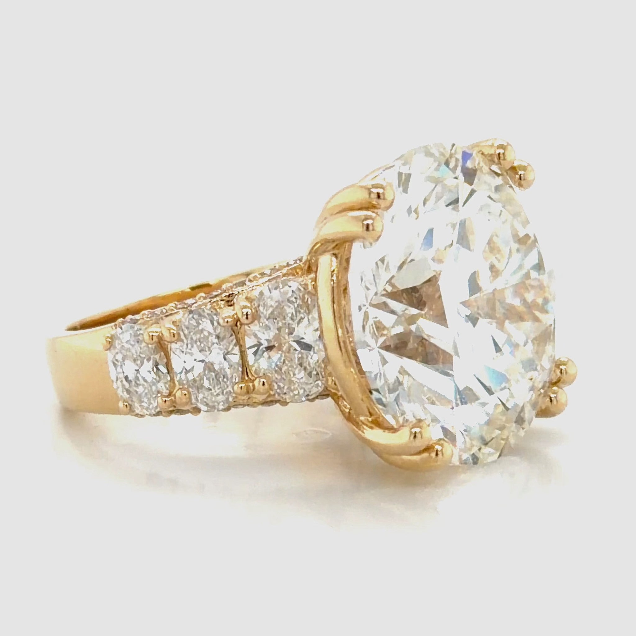 Round brilliant lab-grown diamond engagement ring in 14K yellow gold, shown at an angle with three oval diamonds graduating down each shoulder.
