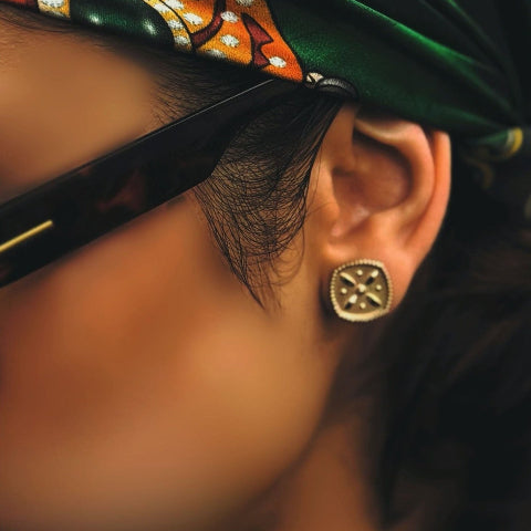 Close-up of an ear wearing a gold earring with a blurred background
