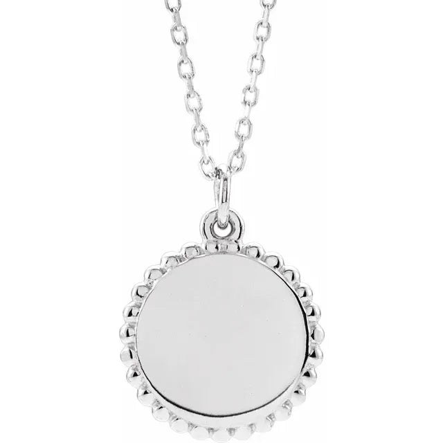 Sterling silver disc pendant with a beaded edge and a smooth polished face, on a cable chain