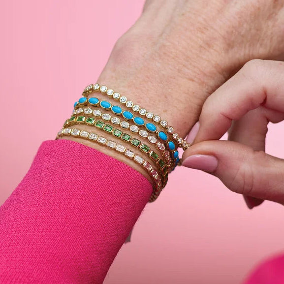 Yellow gold bezel-set tennis bracelet on the wrist, styled in a stack with gemstone bracelets
