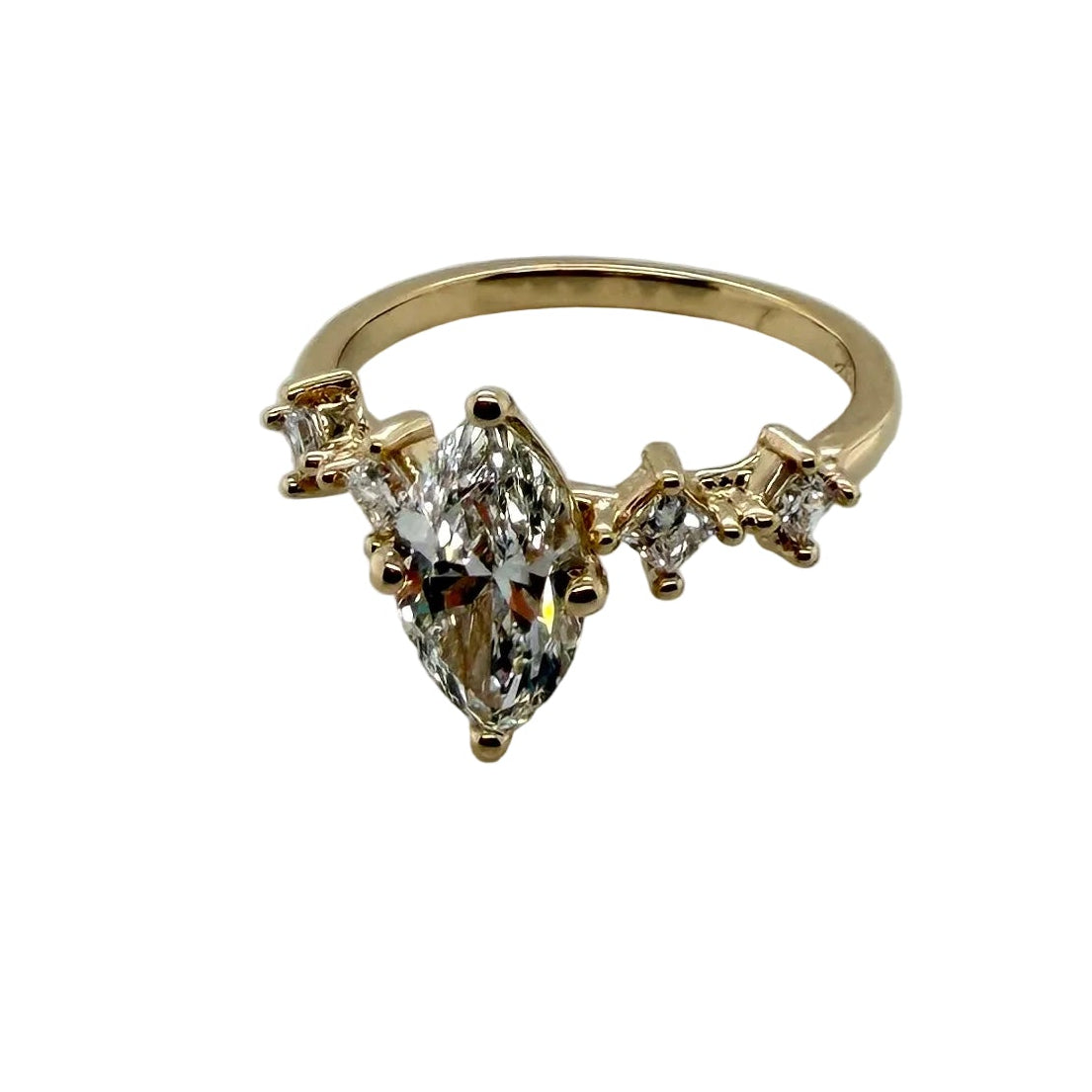The finished marquise ring photographed at an angle, the 1.21 carat marquise diamond flanked by kite and round accent diamonds set asymmetrically along the 14K yellow gold band