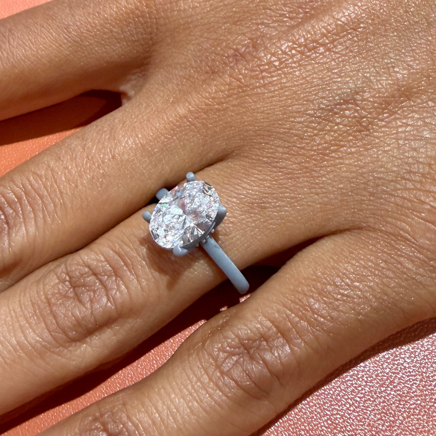The 3D-printed wax pattern of this oval tulip solitaire worn on the hand with the actual 2.24 carat oval diamond set in place — the try-on step before the ring is cast in gold, showing the true scale of the stone on the finger