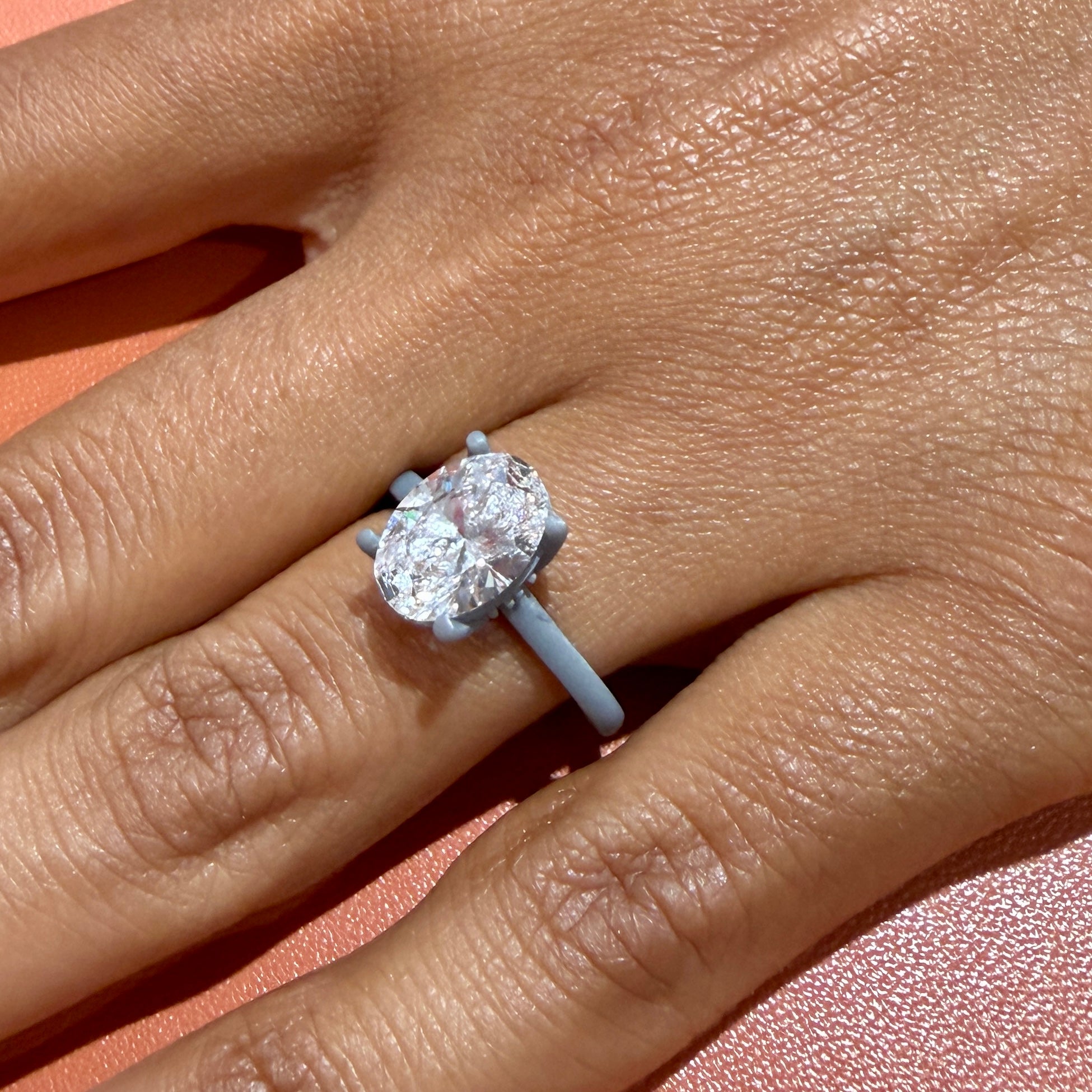 The 3D-printed wax pattern of this oval tulip solitaire worn on the hand with the actual 2.24 carat oval diamond set in place — the try-on step before the ring is cast in gold, showing the true scale of the stone on the finger