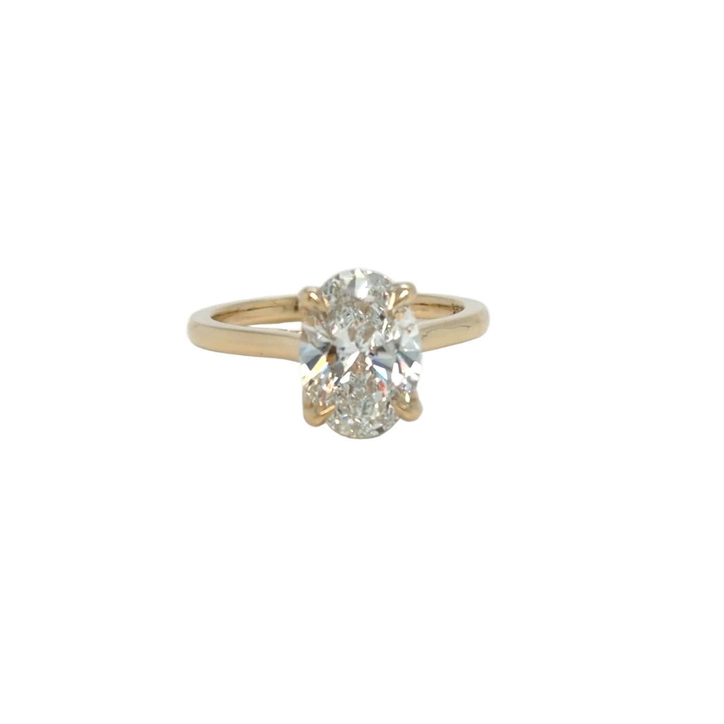 Top view of the 2.24 carat oval lab-grown diamond face-up in four slim yellow gold prongs, the plain band tapering away on either side