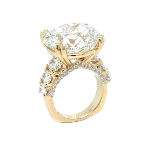 Load image 1 in gallery view. The 24.01 carat round lab-grown diamond at a three-quarter angle, held in paired yellow gold prongs above graduated oval side diamonds and a pave-set band