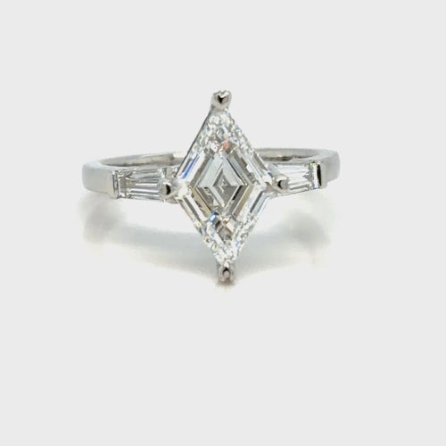 Load image 1 in gallery view. The finished platinum three-stone ring seen face-up, the lozenge-cut diamond set point to point in a prong at each tip, with a tapered baguette diamond angled in on either shoulder