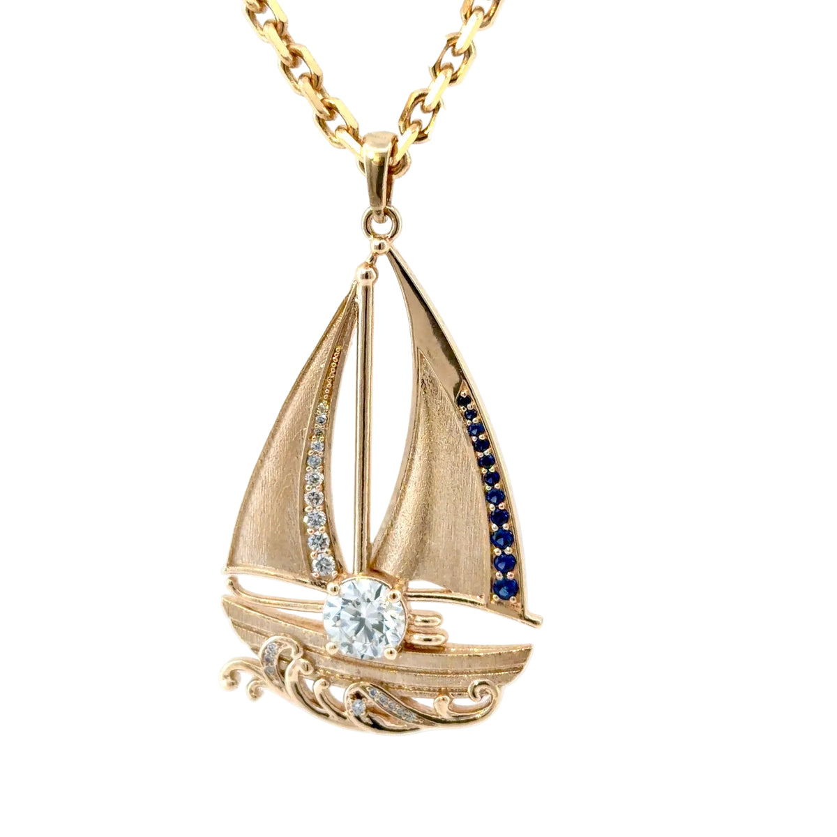 Angled view of the 14K yellow gold sailboat pendant, showing the brushed sails and the diamond-set scrolling waves beneath the hull