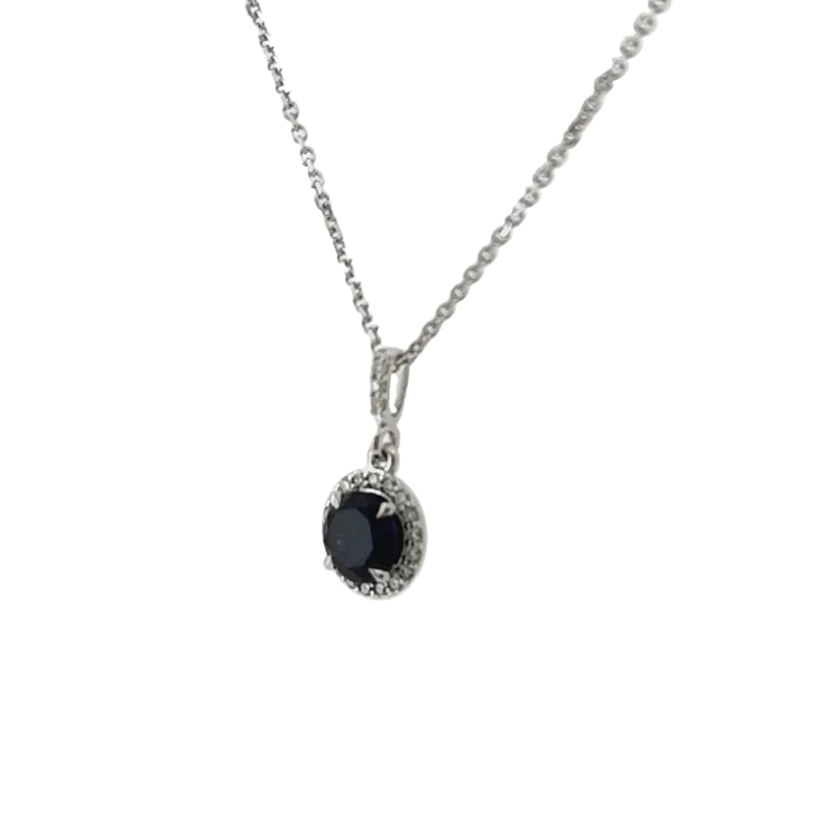 Side view of the blue sapphire halo pendant showing the diamond halo and the diamond-set bail on the white gold chain