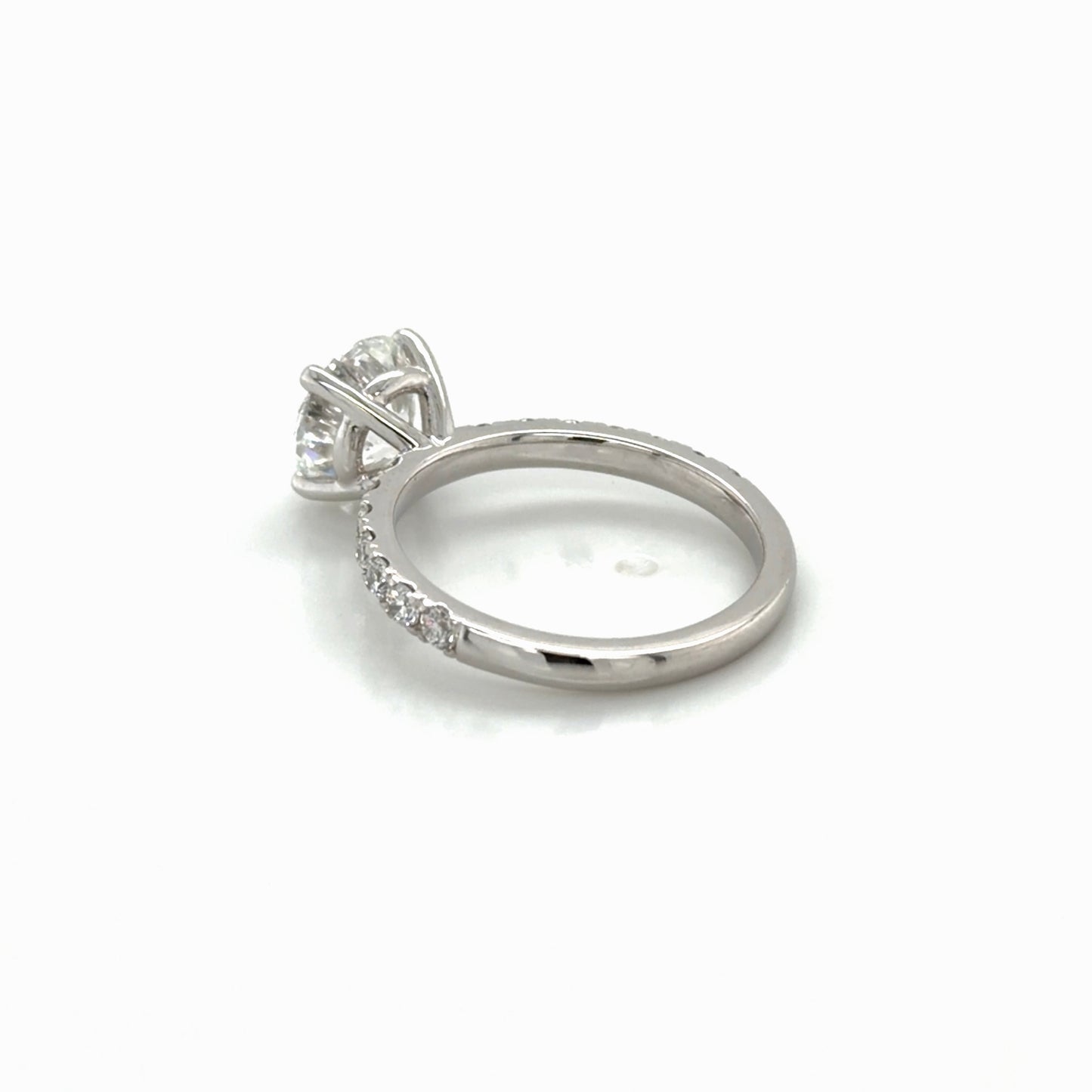 Angled view of the rebuilt 14K white gold four-prong solitaire engagement ring with French-set pavé, Farsi Jewelers