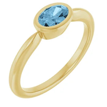 14K yellow gold ring with an oval blue topaz in a bezel setting, shown at an angle