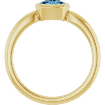 Profile view showing the low bezel setting and tapered band of the blue topaz ring