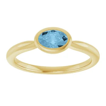 Load image 1 in gallery view. Top view of the oval blue topaz bezel ring in 14K yellow gold, stone set east-west