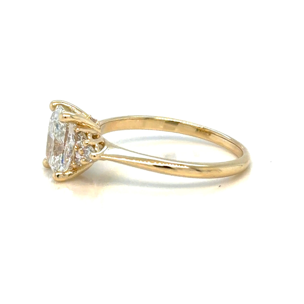 Profile view of the 14K yellow gold cushion-cut engagement ring, showing the four-prong center setting and the split shank running into the shoulder clusters