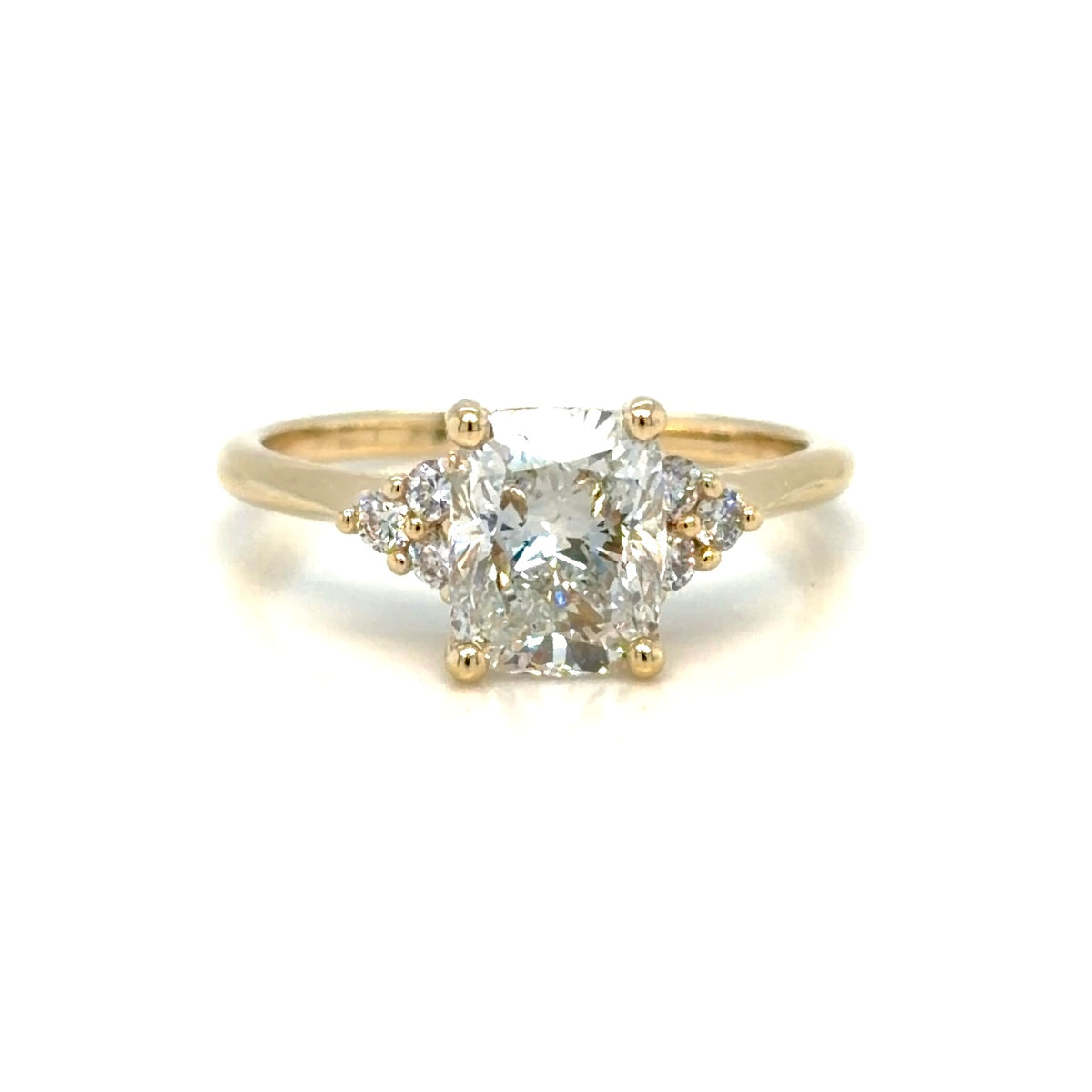 Cushion-cut lab-grown diamond engagement ring in 14K yellow gold seen from above, with a three-stone diamond cluster on each shoulder
