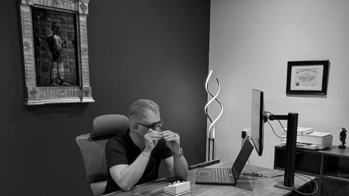 Man sitting at a desk with a laptop and computer monitor in an office making custom jewelry design in sandy springs, GA