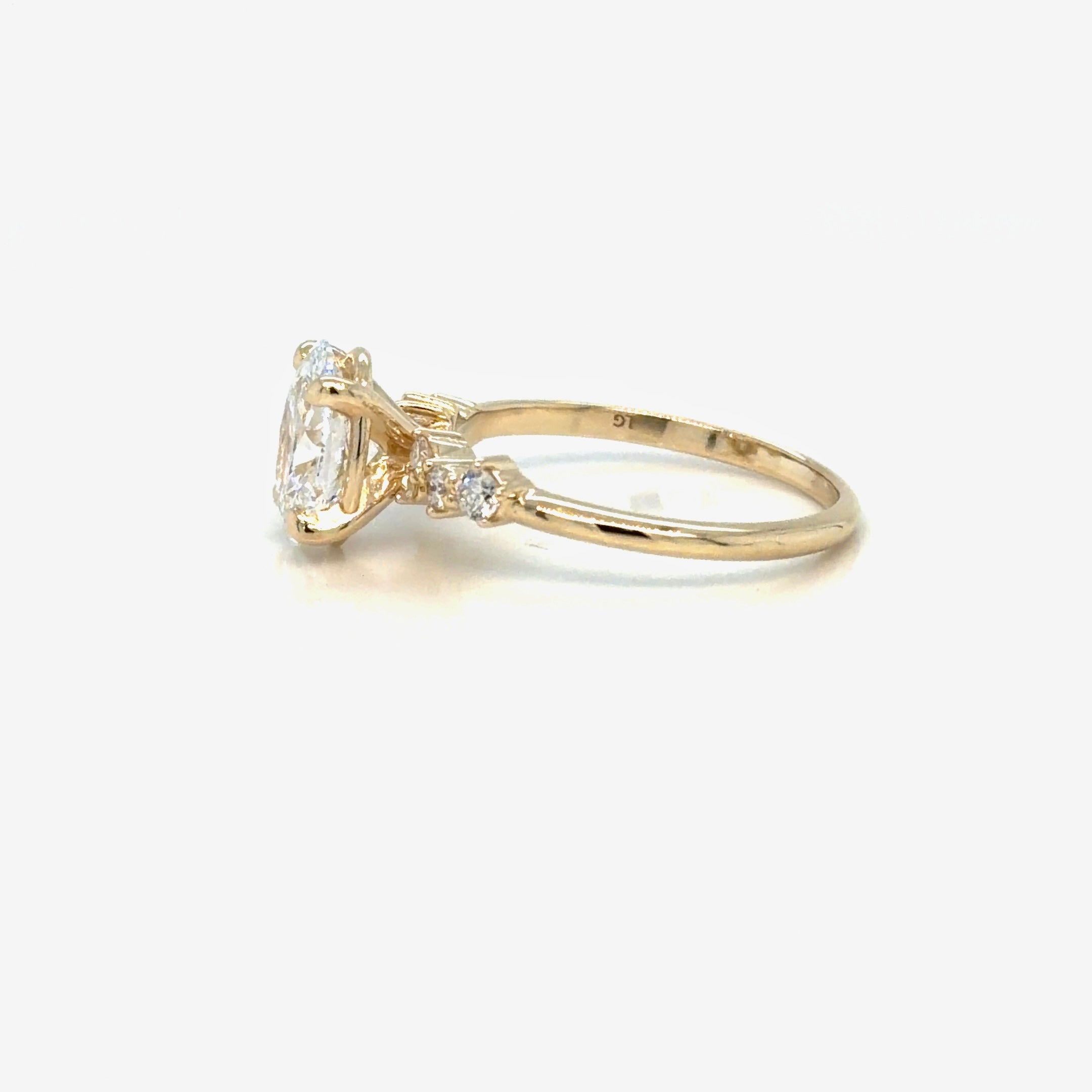 Profile view of the 14K yellow gold oval lab-grown diamond engagement ring, showing the four-prong claw setting open underneath and the shoulder diamonds