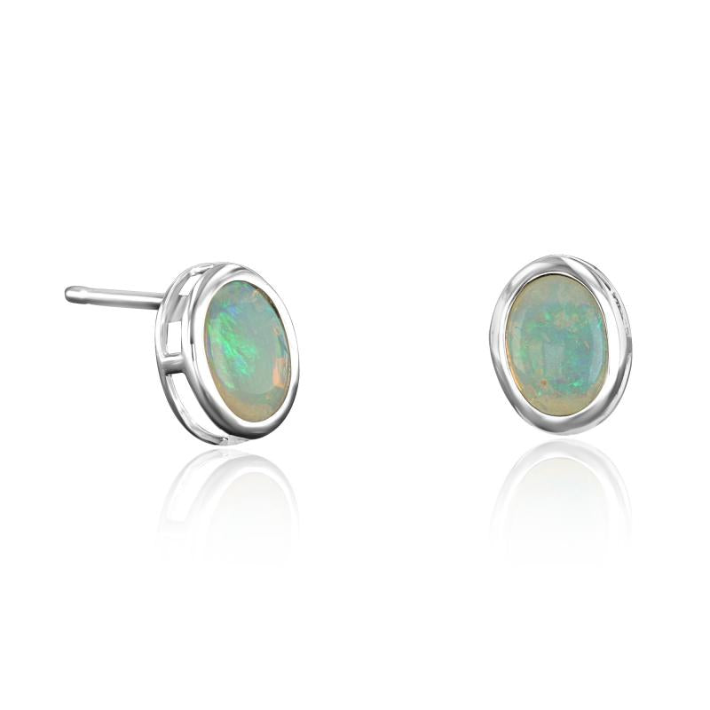 Matched pair of oval opal stud earrings in 14K white gold full bezels, shown face-on and in profile