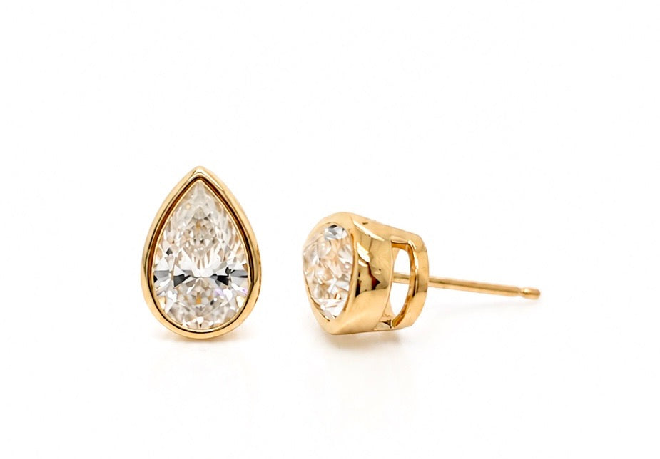 Pear-shape diamond bezel stud earrings in 14K yellow gold shown from the side, showing the depth of the bezel and the friction post