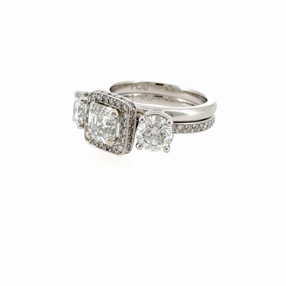 Angled view of the platinum wrap-style ring enhancer fitted around an engagement ring, showing how the two bands sit together