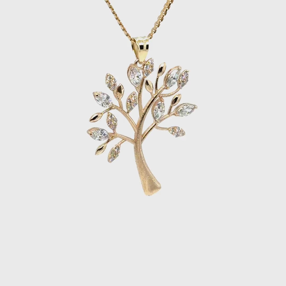 The 14K yellow gold tree of life pendant turning slowly on its chain, catching light across the diamond-set leaves