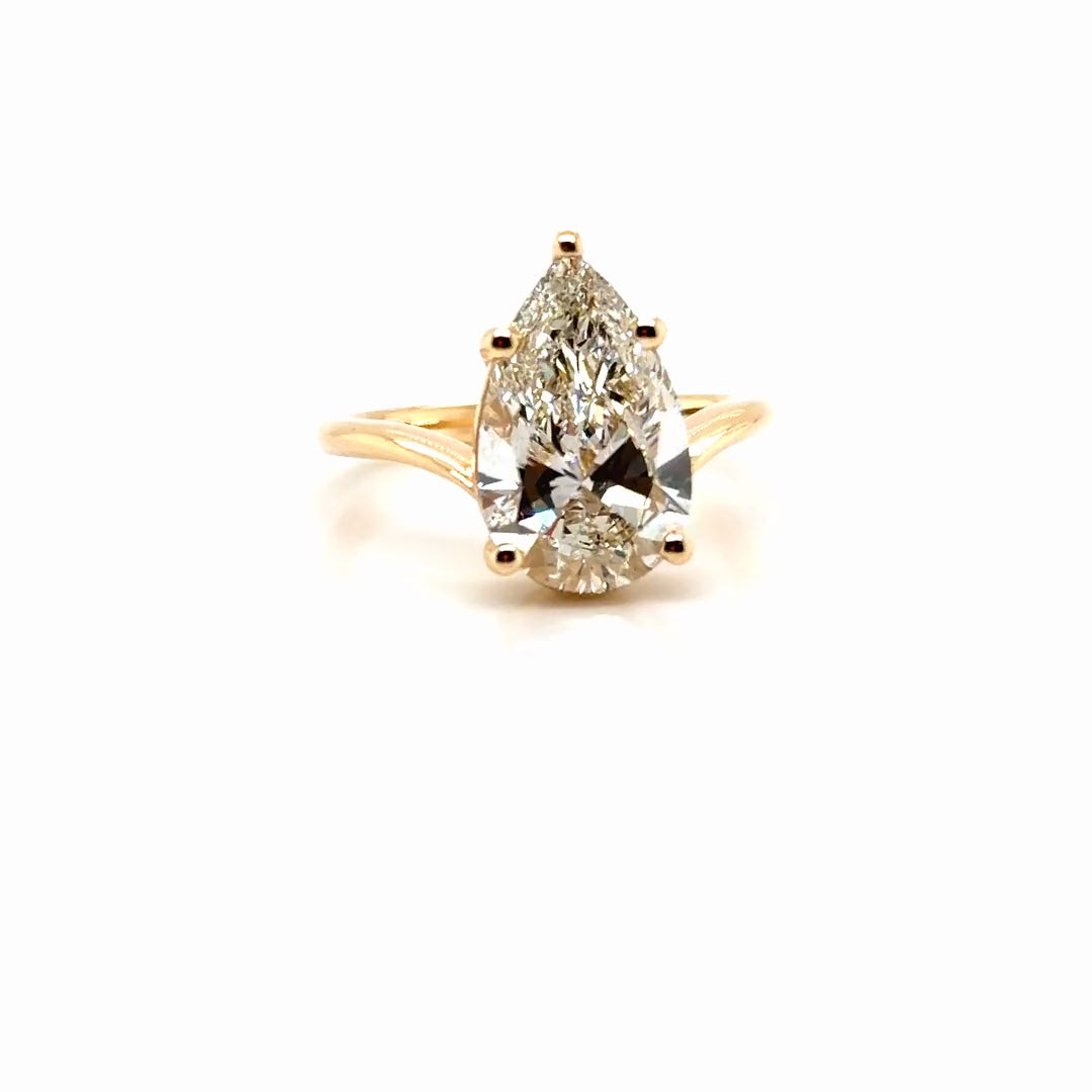 Finished 18K yellow gold bypass engagement ring with a 4 carat pear-cut lab-grown diamond, turning in the light, Farsi Jewelers