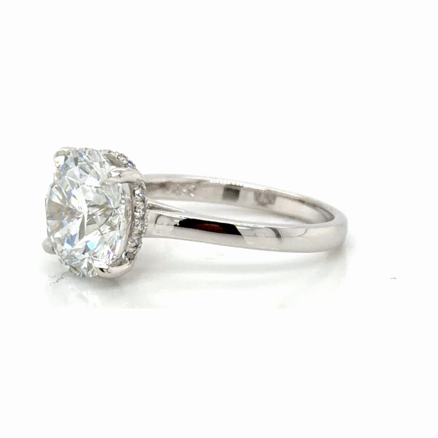 Side profile of the hidden halo ring, the round diamond seen from the edge with the concealed halo visible beneath it and the cathedral shoulders rising to the setting