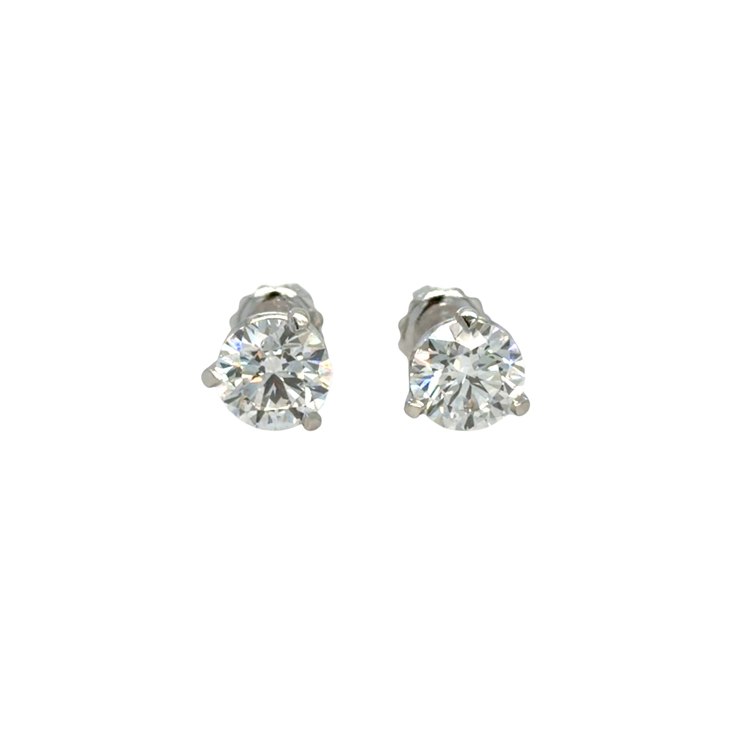 Pair of platinum three-prong martini stud earrings, each set with a round brilliant natural diamond, shown face-on against white