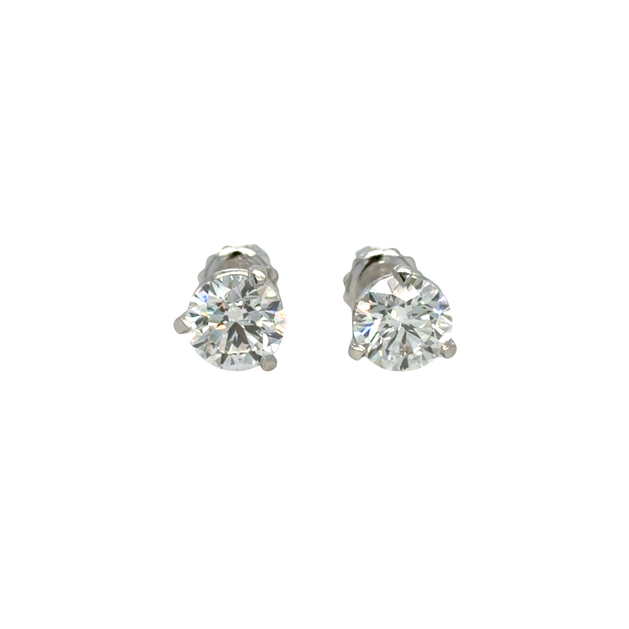 Pair of platinum three-prong martini stud earrings, each set with a round brilliant natural diamond, shown face-on against white